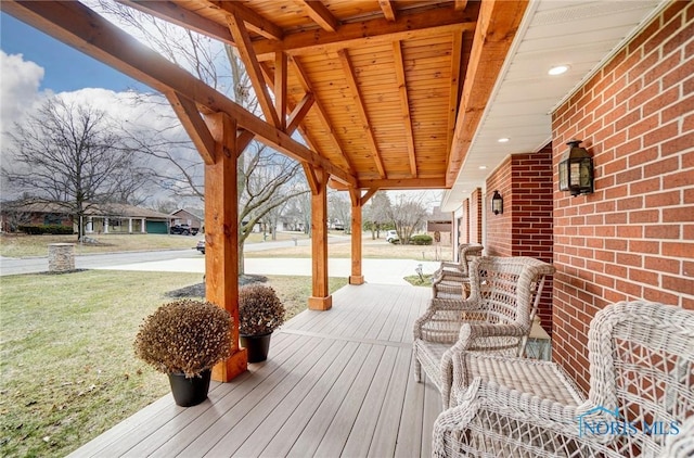 wooden terrace featuring covered porch and a yard