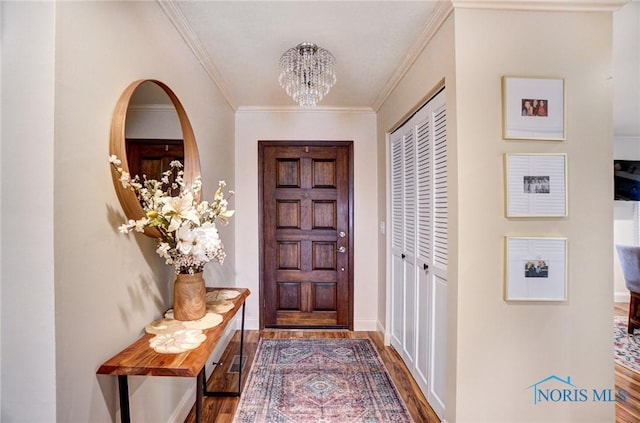 entrance foyer featuring a notable chandelier, baseboards, wood finished floors, and crown molding