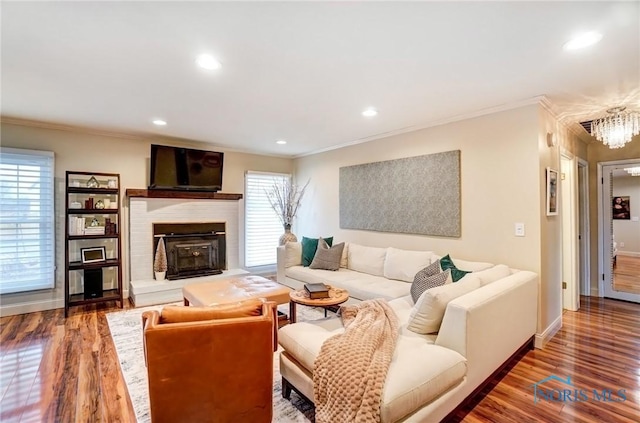 living room with baseboards, ornamental molding, wood finished floors, and recessed lighting