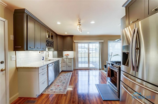 kitchen featuring glass insert cabinets, appliances with stainless steel finishes, dark wood-style flooring, dark brown cabinets, and backsplash