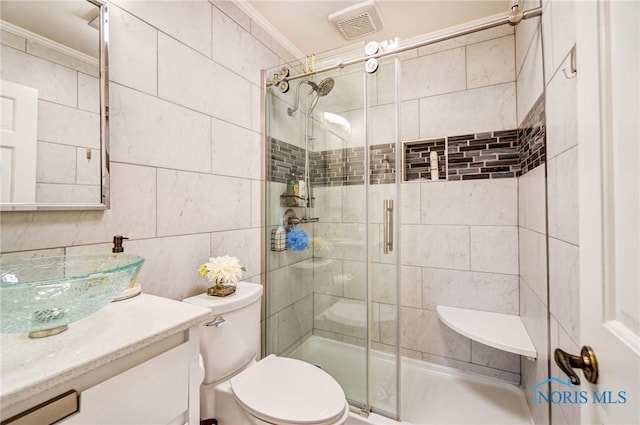 full bath with toilet, vanity, tile walls, ornamental molding, and a shower stall