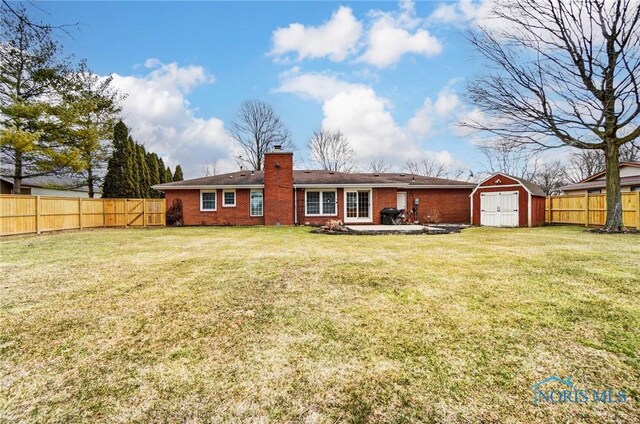 rear view of house with a fenced backyard, a chimney, a storage unit, and an outdoor structure