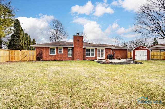 back of house featuring an outbuilding, a fenced backyard, a storage shed, brick siding, and a chimney