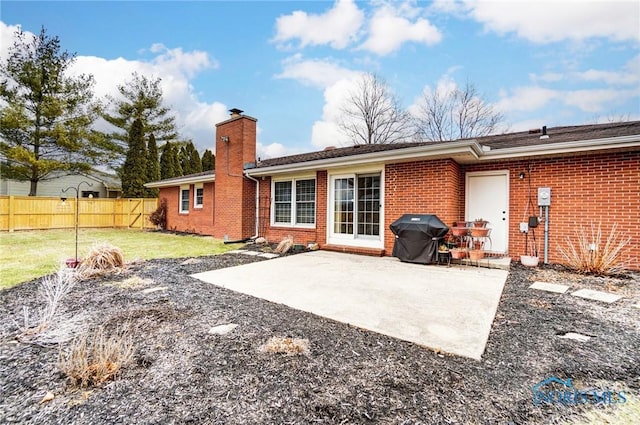 back of property featuring a patio area, fence, a chimney, and brick siding