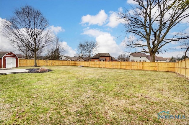 view of yard with a fenced backyard, a storage unit, and an outbuilding