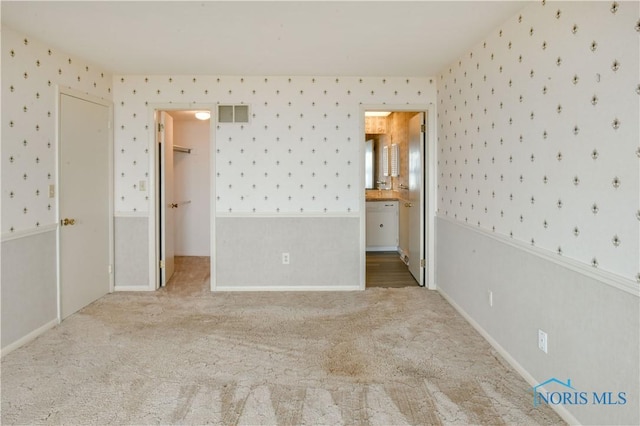 empty room featuring wainscoting, carpet flooring, visible vents, and wallpapered walls