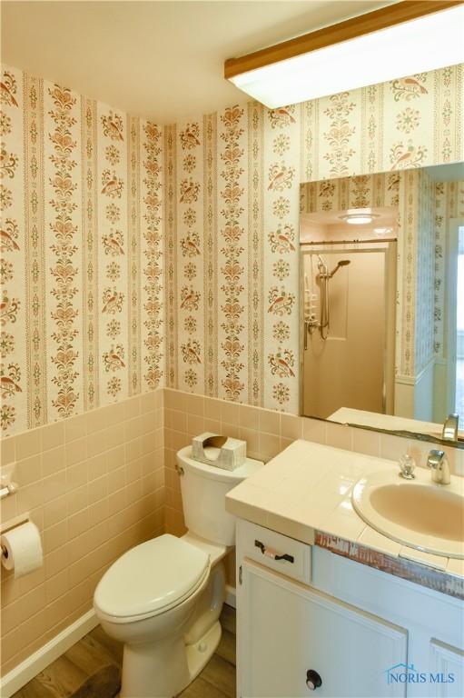 bathroom with a wainscoted wall, tile walls, and wallpapered walls