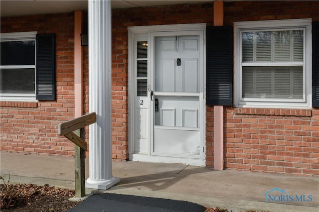 view of exterior entry with covered porch and brick siding