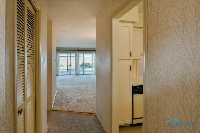 hall featuring baseboards, carpet flooring, and wallpapered walls