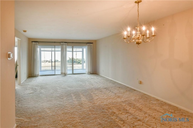 carpeted spare room featuring baseboards and a notable chandelier