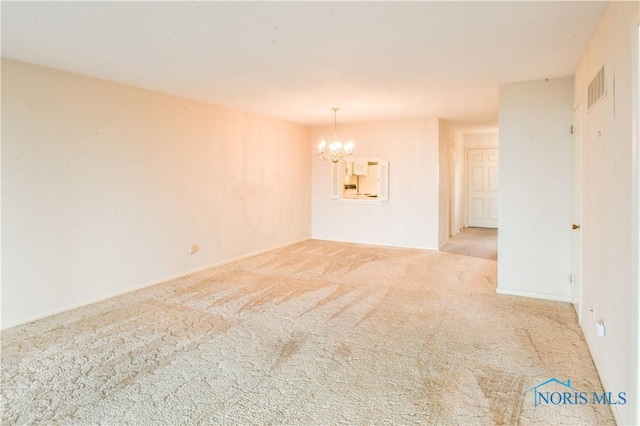 empty room featuring carpet, visible vents, and a notable chandelier