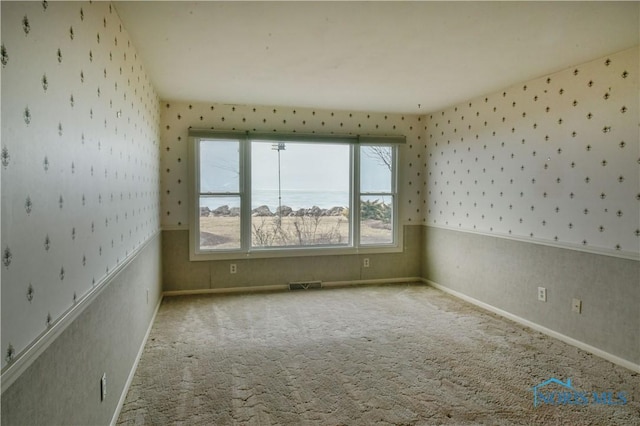 spare room with wainscoting, carpet flooring, visible vents, and wallpapered walls