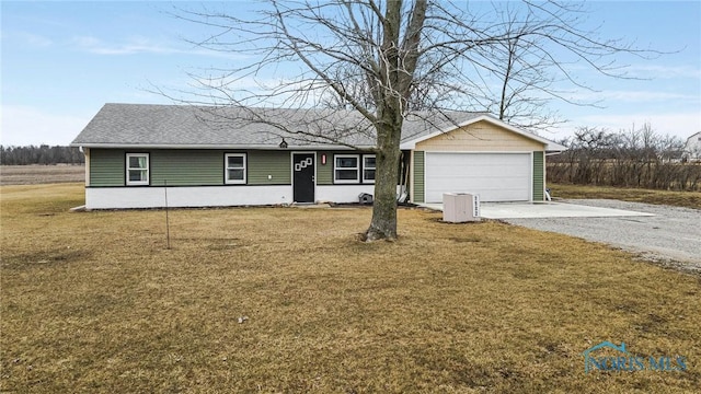 ranch-style home featuring an outbuilding, an attached garage, a shingled roof, a front yard, and gravel driveway