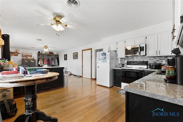 kitchen with visible vents, stainless steel microwave, freestanding refrigerator, white cabinets, and range with electric cooktop