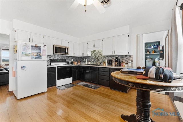 kitchen featuring stainless steel microwave, electric range, freestanding refrigerator, white cabinets, and a sink