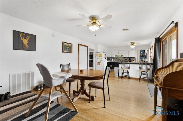 dining space with light wood-style floors, visible vents, and ceiling fan