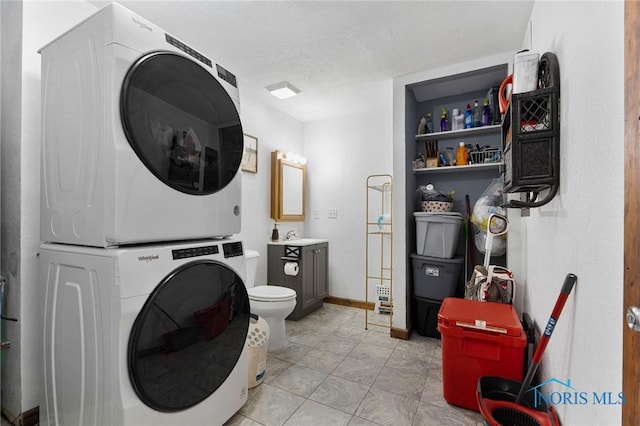 bathroom with stacked washer and dryer, vanity, and baseboards