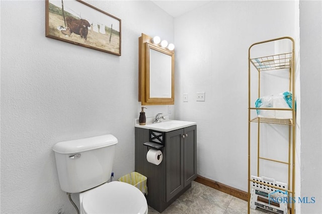 bathroom with vanity, toilet, and baseboards