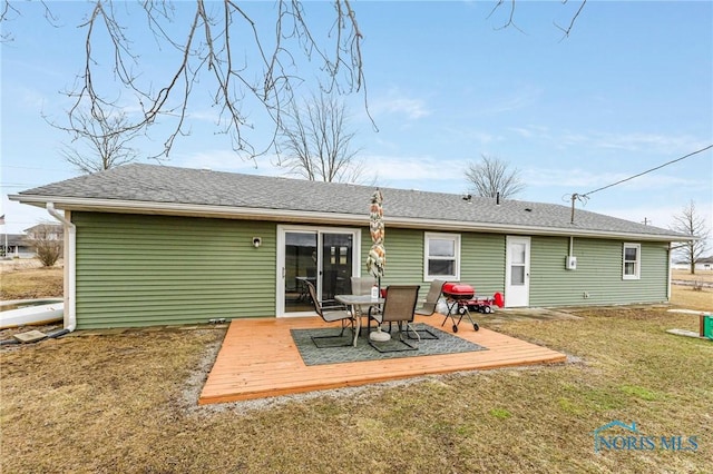 rear view of house featuring a shingled roof, a yard, and a deck