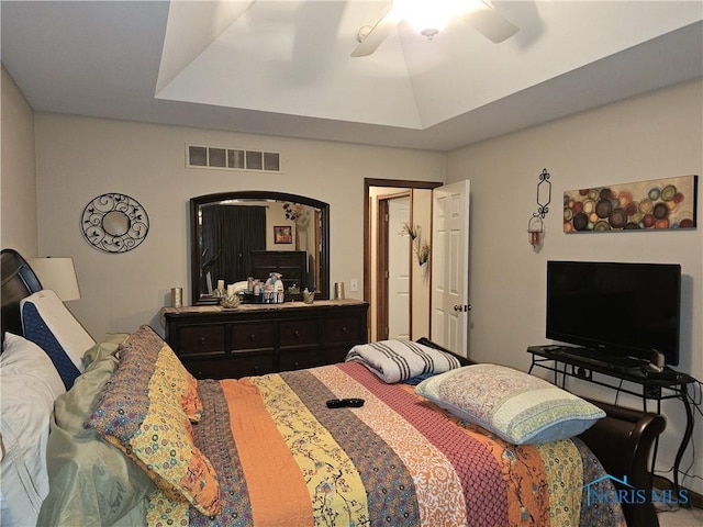 bedroom featuring a ceiling fan, visible vents, and a tray ceiling