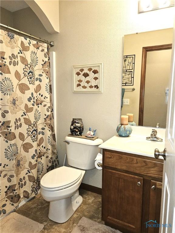 bathroom with toilet, a shower with curtain, baseboards, and vanity