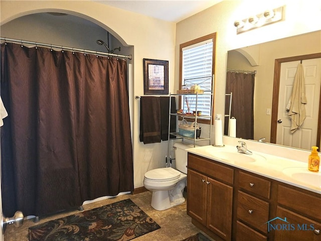 full bath with double vanity, curtained shower, toilet, and a sink