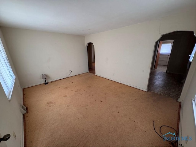 spare room with arched walkways and carpet flooring