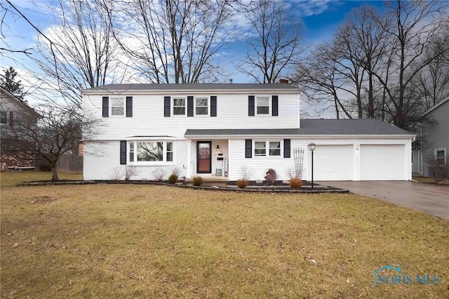 colonial inspired home with an attached garage, concrete driveway, a chimney, and a front yard