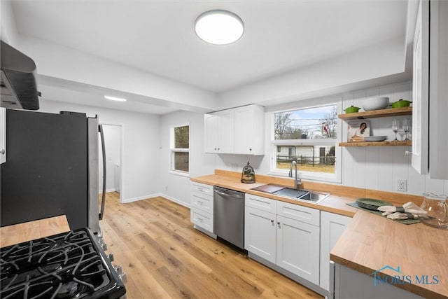 kitchen featuring plenty of natural light, butcher block countertops, appliances with stainless steel finishes, and a sink