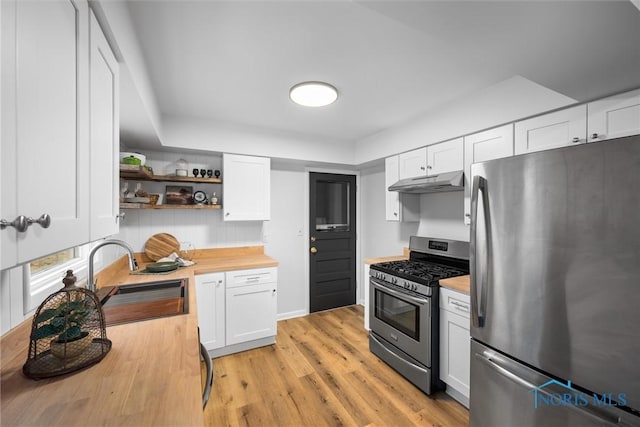 kitchen featuring open shelves, appliances with stainless steel finishes, a sink, butcher block countertops, and under cabinet range hood