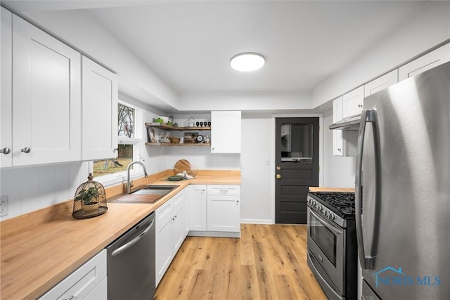 kitchen with stainless steel appliances, white cabinetry, a sink, and open shelves