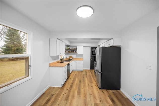 kitchen featuring open shelves, appliances with stainless steel finishes, white cabinetry, and a healthy amount of sunlight