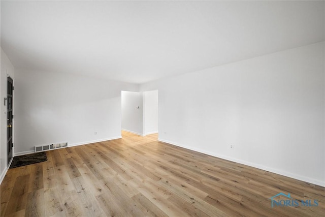 empty room with light wood-style flooring, visible vents, and baseboards