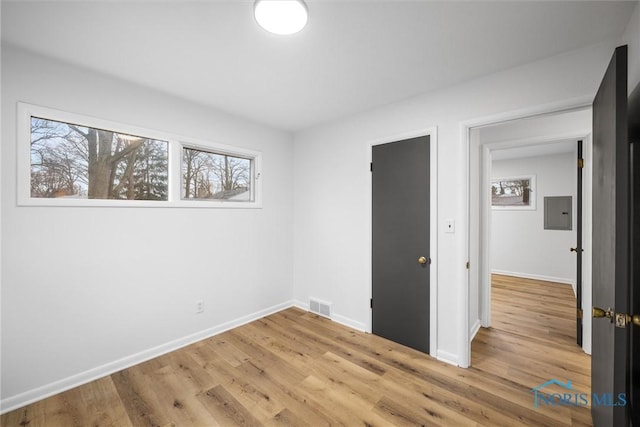 unfurnished bedroom featuring light wood-type flooring, electric panel, and baseboards