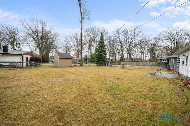 view of yard featuring a patio area, a shed, fence, and an outbuilding