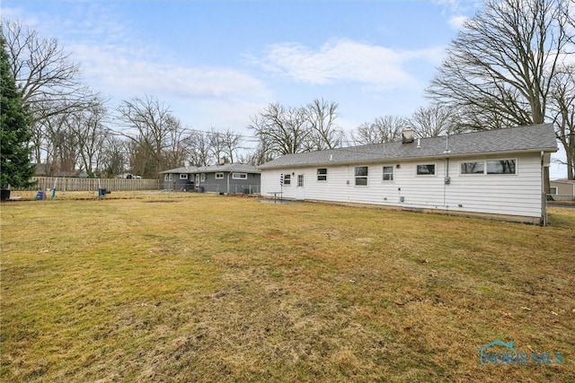 back of property featuring a lawn and fence