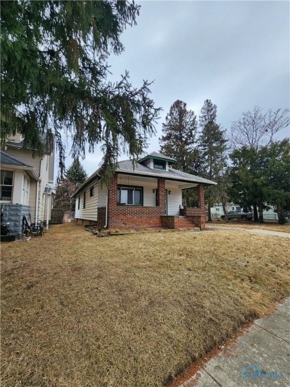 bungalow-style house with brick siding and a front lawn