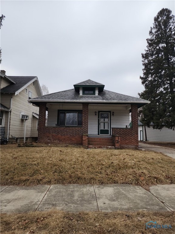 view of front facade featuring brick siding, a front lawn, and a porch