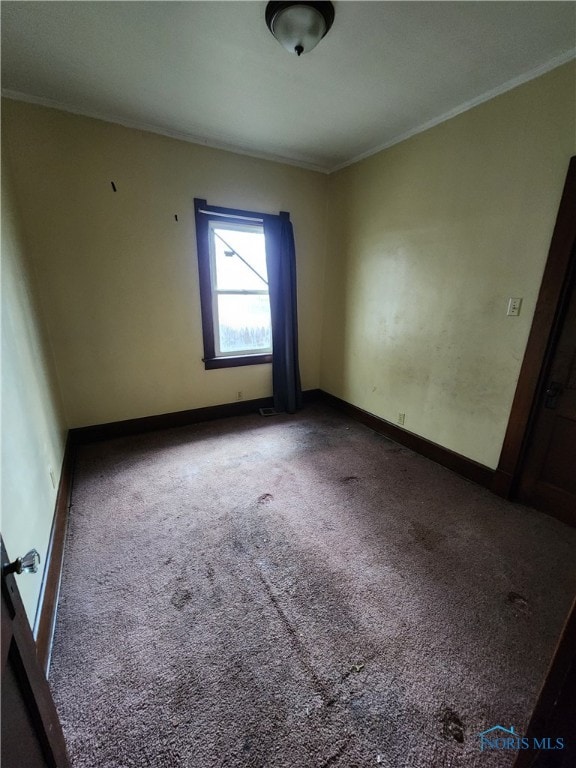 empty room featuring carpet floors, ornamental molding, and baseboards