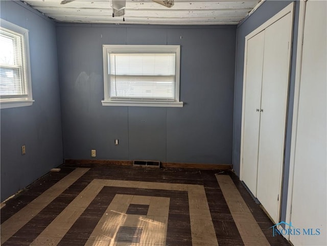 unfurnished bedroom with a closet, visible vents, and multiple windows