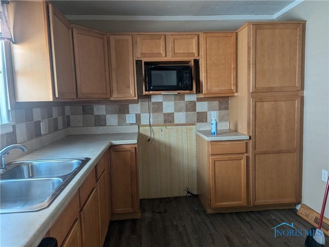 kitchen with dark wood-type flooring, a sink, backsplash, black microwave, and light countertops