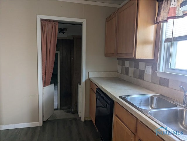 kitchen featuring dark wood finished floors, dishwasher, light countertops, decorative backsplash, and a sink