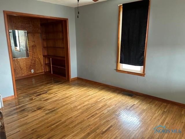 spare room with a healthy amount of sunlight, visible vents, baseboards, and wood finished floors