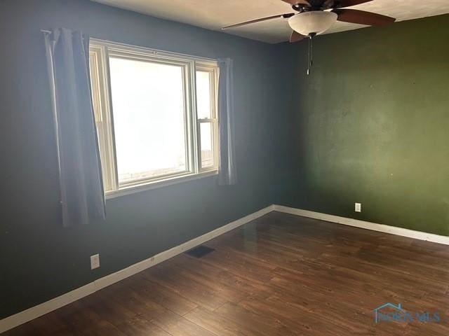 spare room featuring dark wood-style floors, baseboards, and a ceiling fan