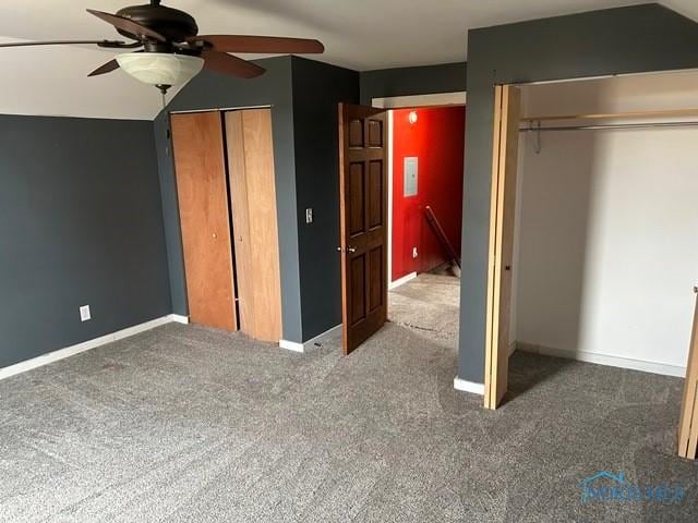 unfurnished bedroom featuring baseboards, two closets, and carpet flooring