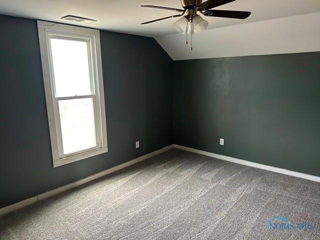 additional living space featuring baseboards, visible vents, ceiling fan, vaulted ceiling, and dark carpet