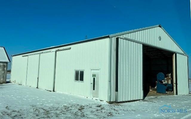 snow covered structure featuring an outdoor structure and an outbuilding