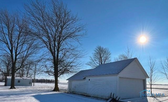 snow covered garage with a detached garage