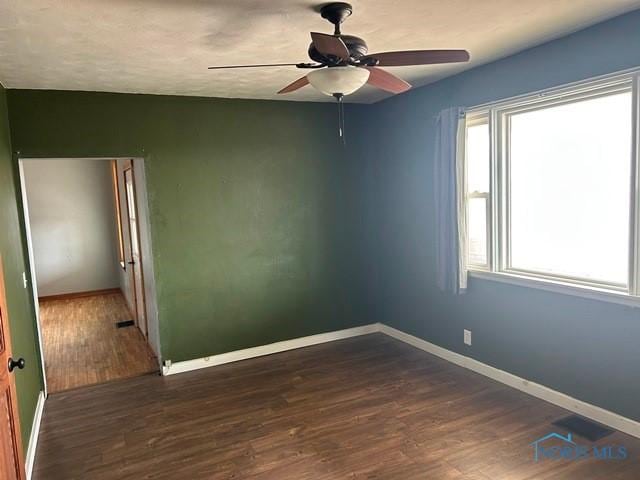 unfurnished room featuring dark wood-type flooring, baseboards, and a ceiling fan