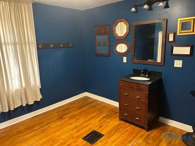 bathroom featuring vanity, wood finished floors, visible vents, and baseboards